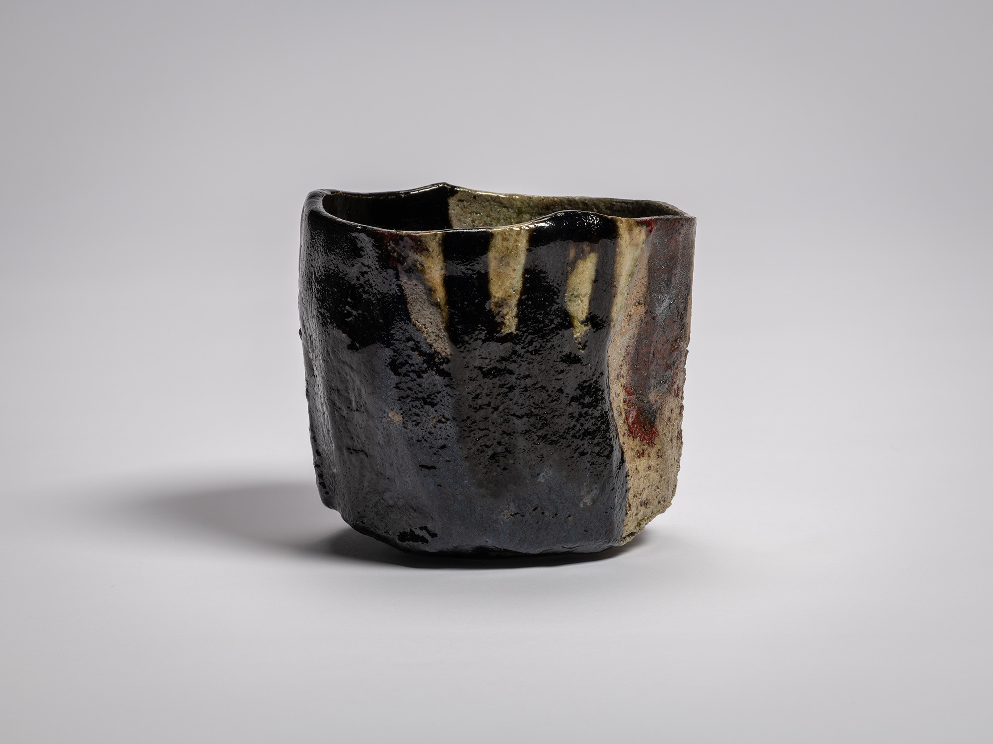 Kōshū (Mountain Peak) by Raku Jikinyū XV, showing a glossy black surface with several cream-colored...