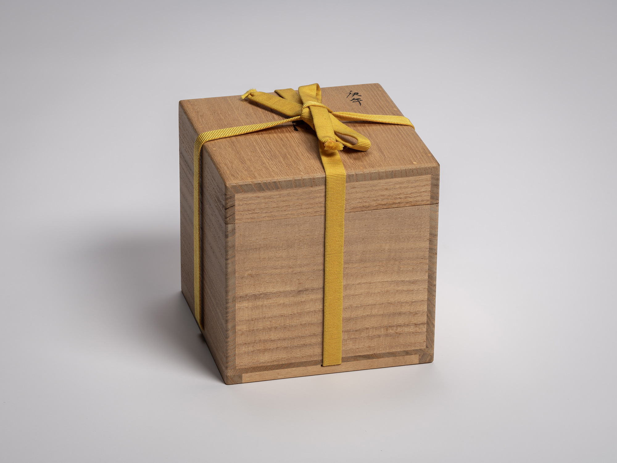 Wooden box for Kōshū (Mountain Peak) by Raku Jikinyū XV, secured with a yellow tying cord; the...